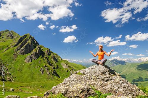 Young woman sitting in yoga pose in mountains