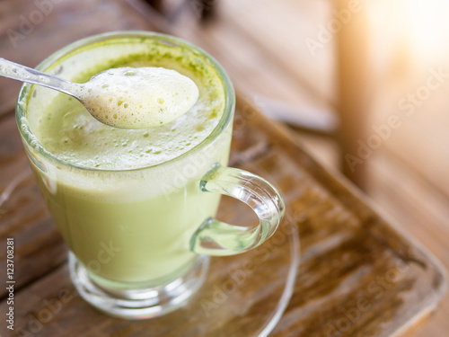 Hot green tea with milk in glass mug.