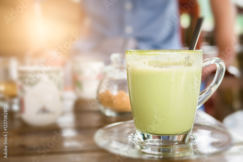 Hot green tea with milk in glass mug.