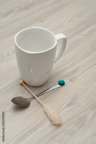 A white mug with a sugar stick and a teaspoon 