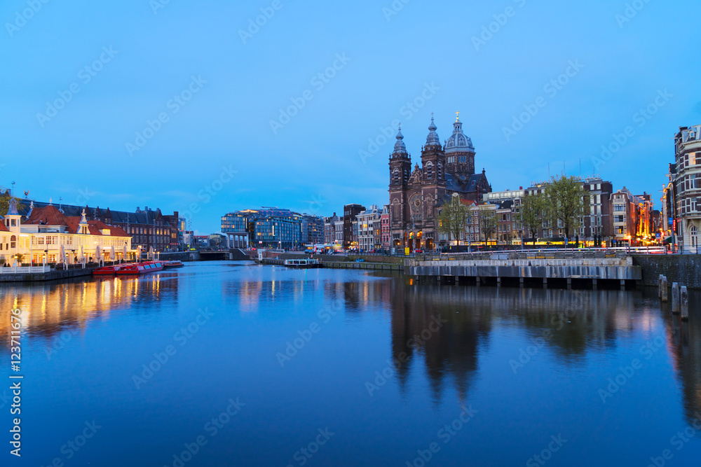 Amsterdam skyline with Church of St Nicholas over old town canal at night, Amsterdam, Holland