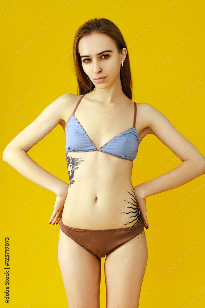 Skinny girl on a yellow background in beautiful lingerie - obrazy, fototapety, plakaty 