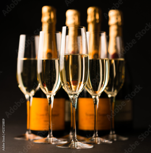 Five sparkling champagne filled glasses flutes with Bottles isolated on Black background for use alone or as a design element