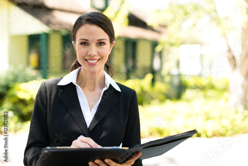 Photography Attractive businesswoman real estate agent broker with bungalow house in backgro