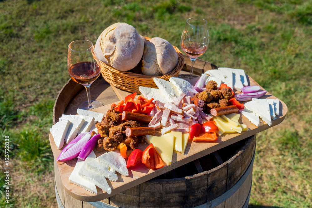 Harvesting season traditional Romanian food plate with cheese, bread, sausages, onions and red wine in glass