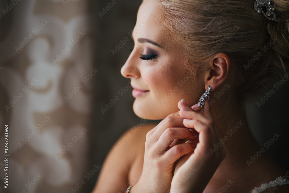 Daydreaming bride touches her earring delcately standing behind