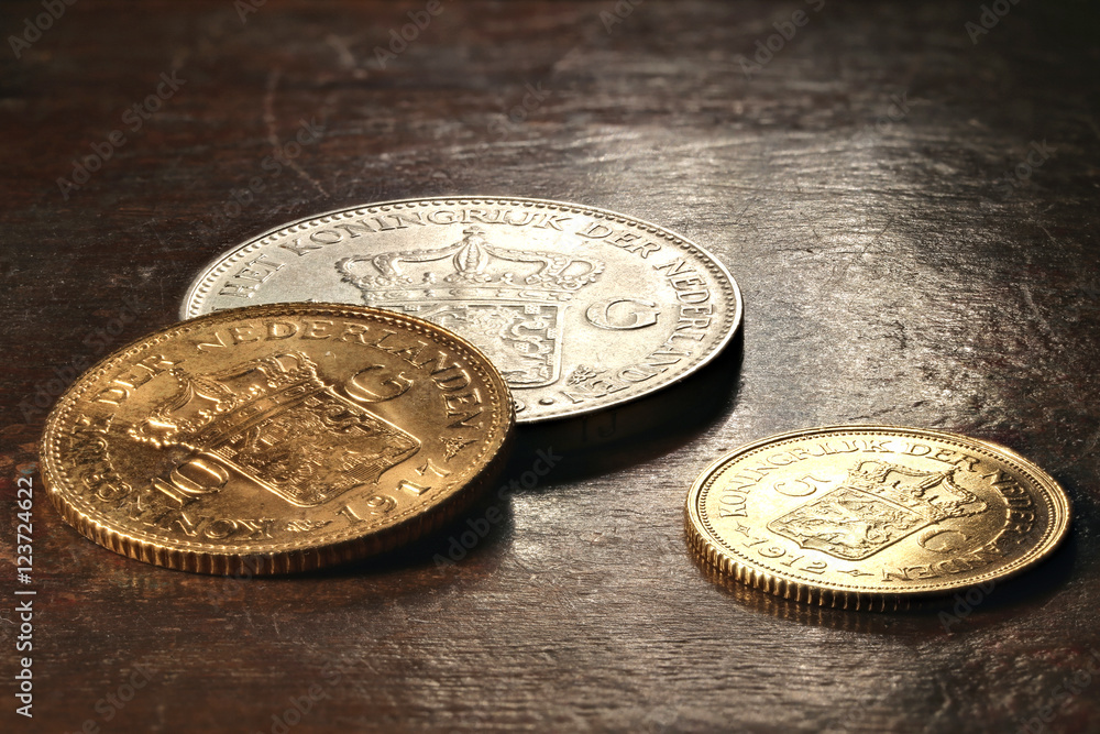 Niederländische Silber- und Goldmünzen auf rustikalem Holztisch Niederländische Silber- und Goldmünzen auf rustikalem Holztisch
