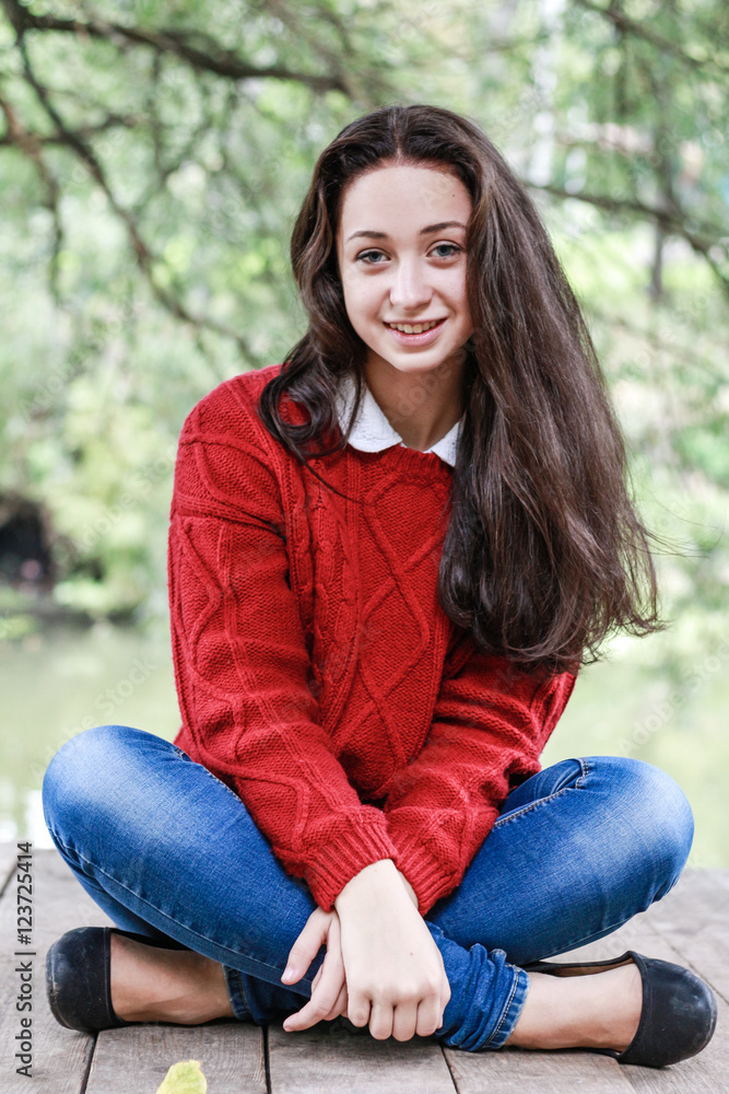 Young girl laughing sitting on a wooden floor in the park. Young girl laughing sitting on a wooden floor in the park.