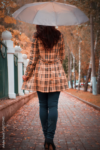 woman with umbrella walking in the autumn park