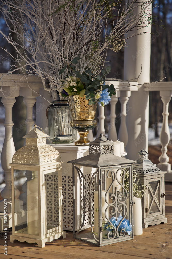 Fototapeta premium Wedding decor. White and grey steel lanterns surround a vase wit