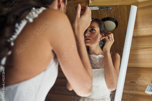 Tender bride adjusts her hair looking in the mirror