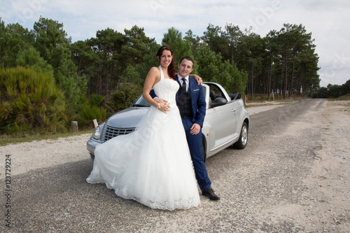 Lovely cute groom and bride on a grey convertible car posing © OceanProd