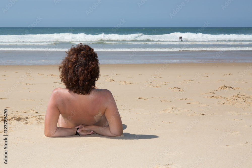 Fototapeta premium Brunette woman on the beach backside to camera