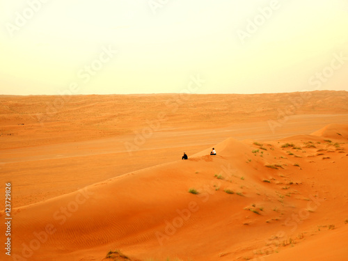 Two women sitting in the Wahiba desert, Oman