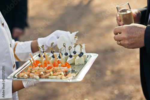 Waiter is holding a server with the tasty appetizers