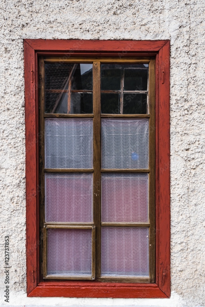Rotes Holzkastenfenster mit Gardinen