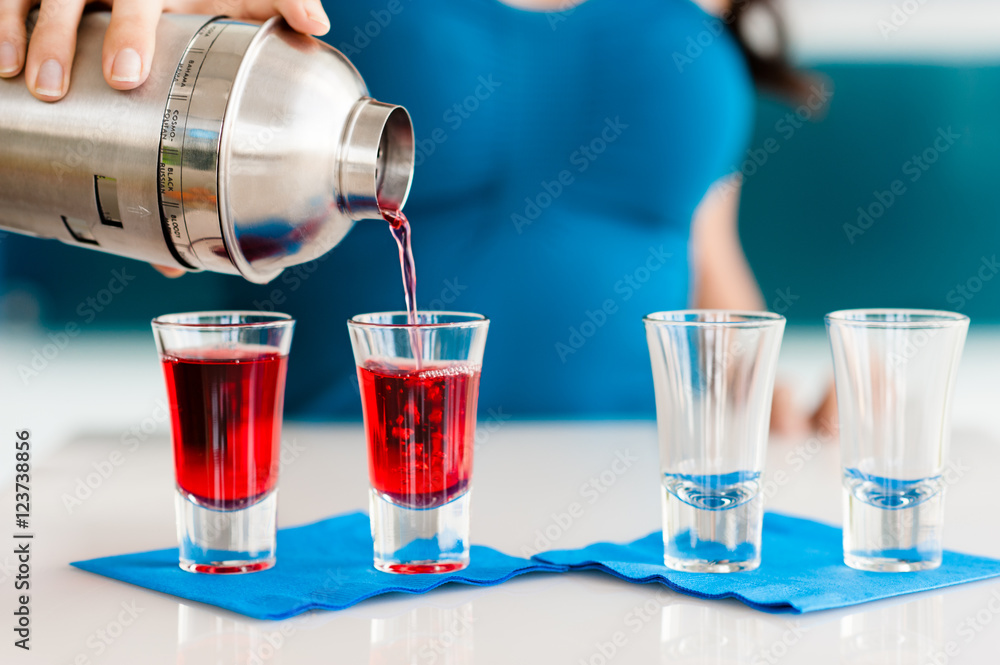 Young Woman Bartender Pouring Red Shot of Liquor Young Woman Bartender Pouring Red Shot of Liquor
