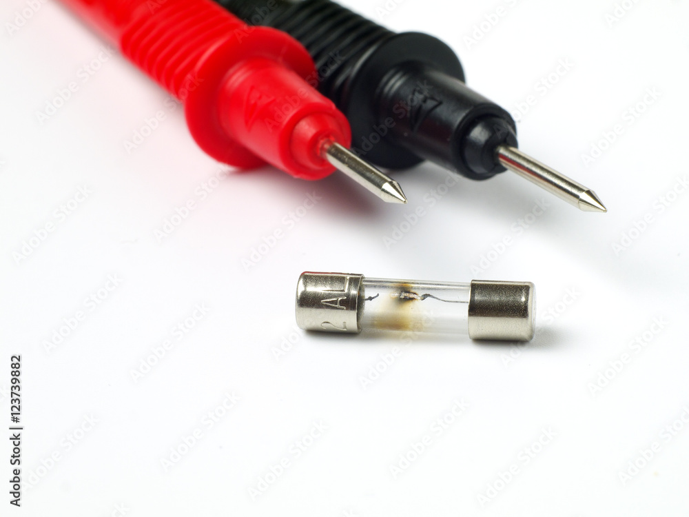 blown fuse macro with multimeter probes in background, white background, shallow depth of field blown fuse macro with multimeter probes in background, white background, shallow depth of field