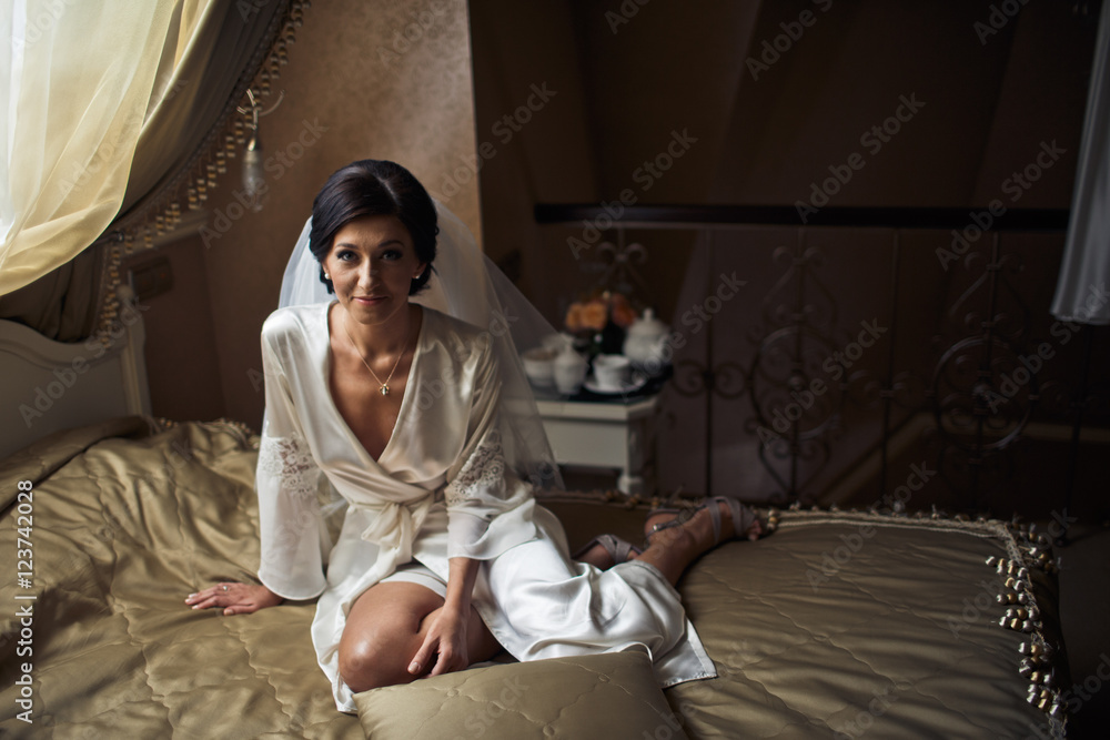 Fototapeta premium The charming bride sits on the bed