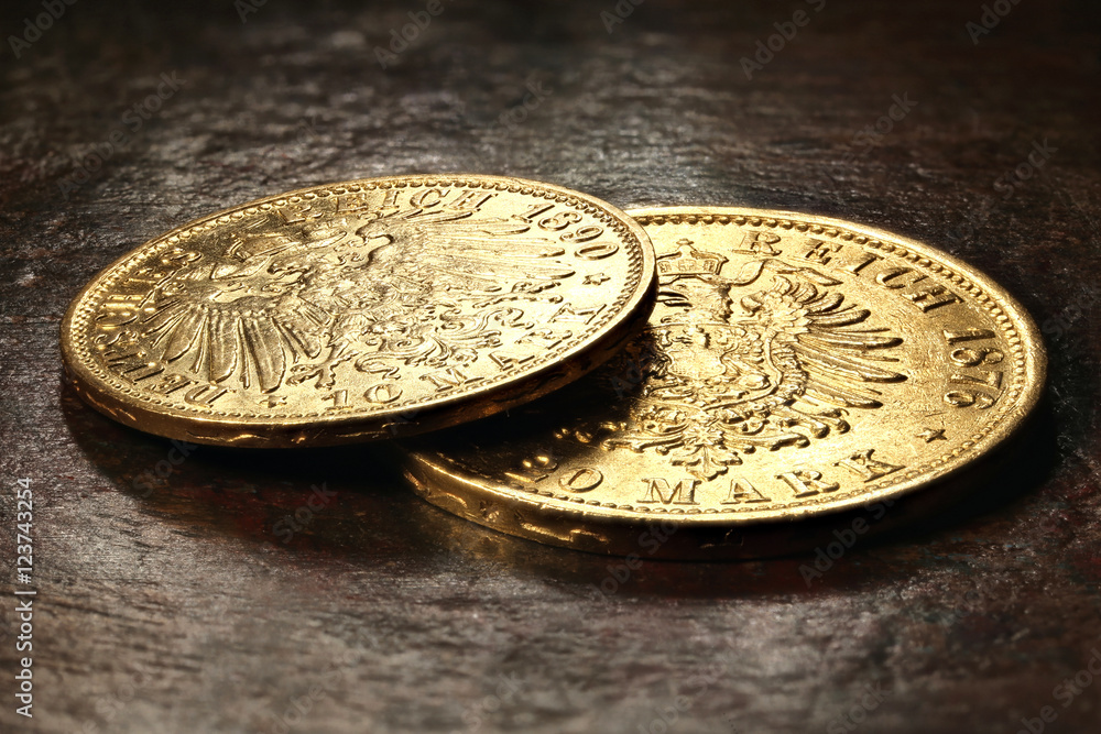 10 und 20 Reichsmark Goldmünzen (Hamburg) auf rustikalem Holztisch 10 und 20 Reichsmark Goldmünzen (Hamburg) auf rustikalem Holztisch