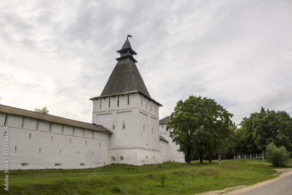 The white wall of the monastery and square hipped tower.