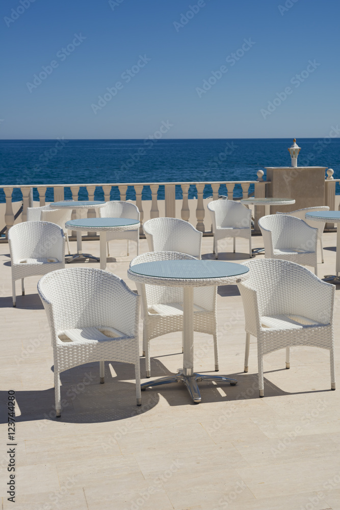 Empty cafe on the terrace on a summer day, without guests, white chairs and tables, selective focus