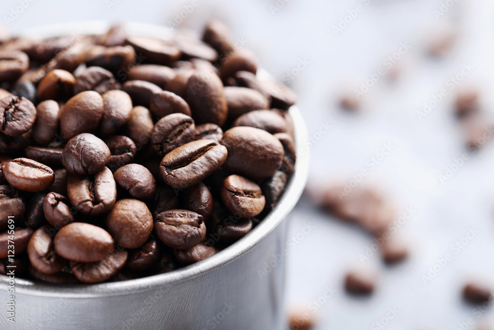 Fototapeta premium Roasted coffee beans in mug on grey table