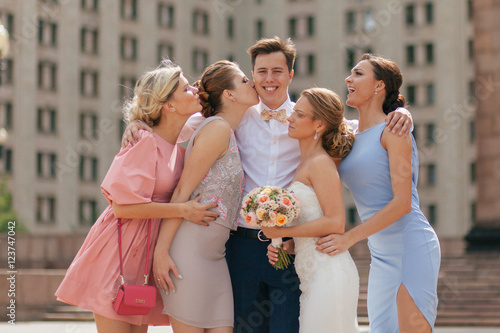 Bridesmaids are kissing a groom in the wedding day