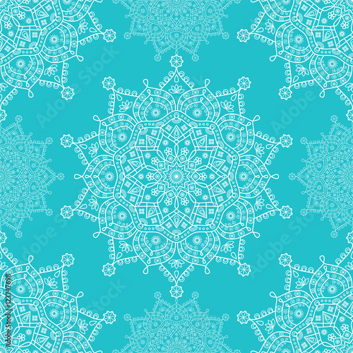 Seamless mandala snowflakes pattern. Winter theme festive wallpaper. White floral snowflakes on turquoise blue background.