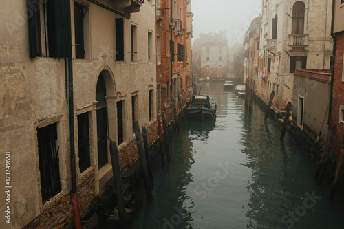 Lonely gondola stands in the water in a channel full of fog