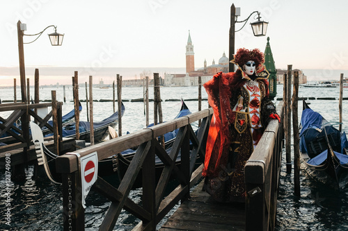 Woman in rich red carnival costume stands on the wooden bridge t © nastasenko