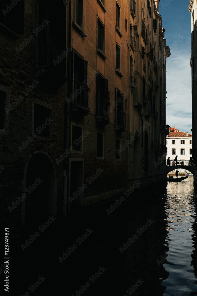 Gondola floats under an old bridge over a Venice channel