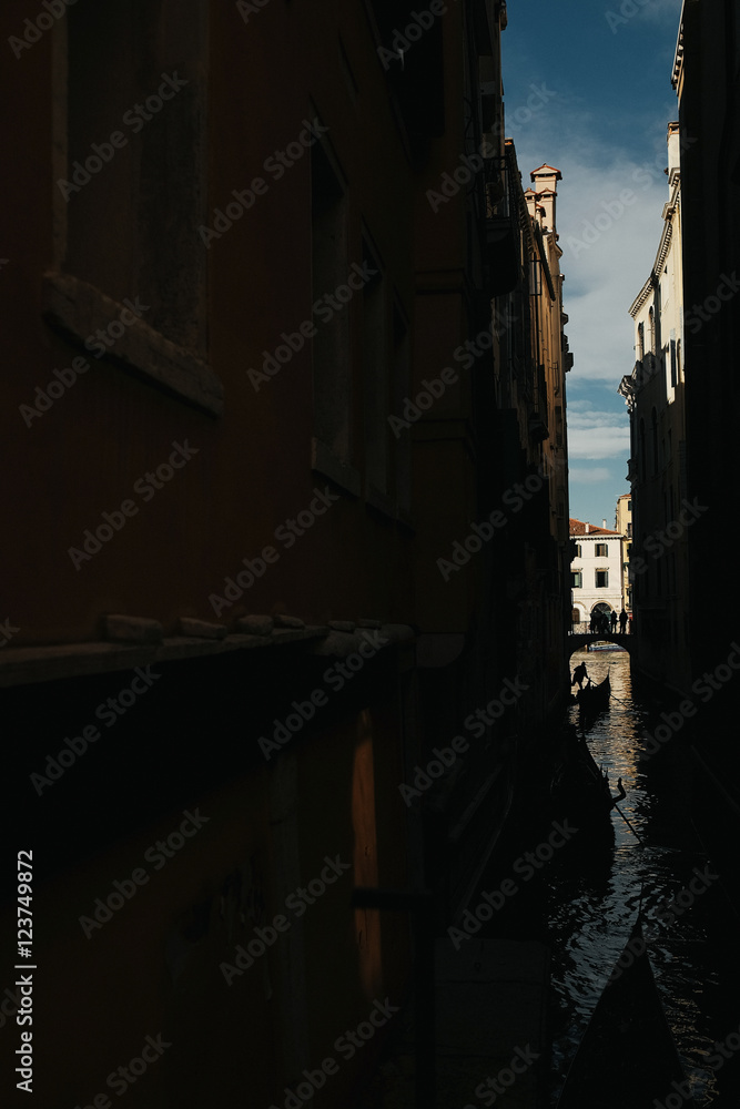 A dark picture of a channel in Venice where a gondola floats