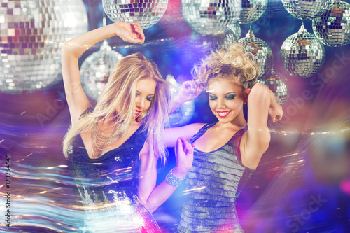 Two young women dancing at night disco club