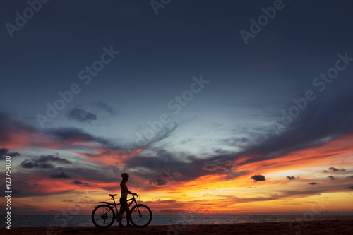 Young woman with bicycle at the sea beach