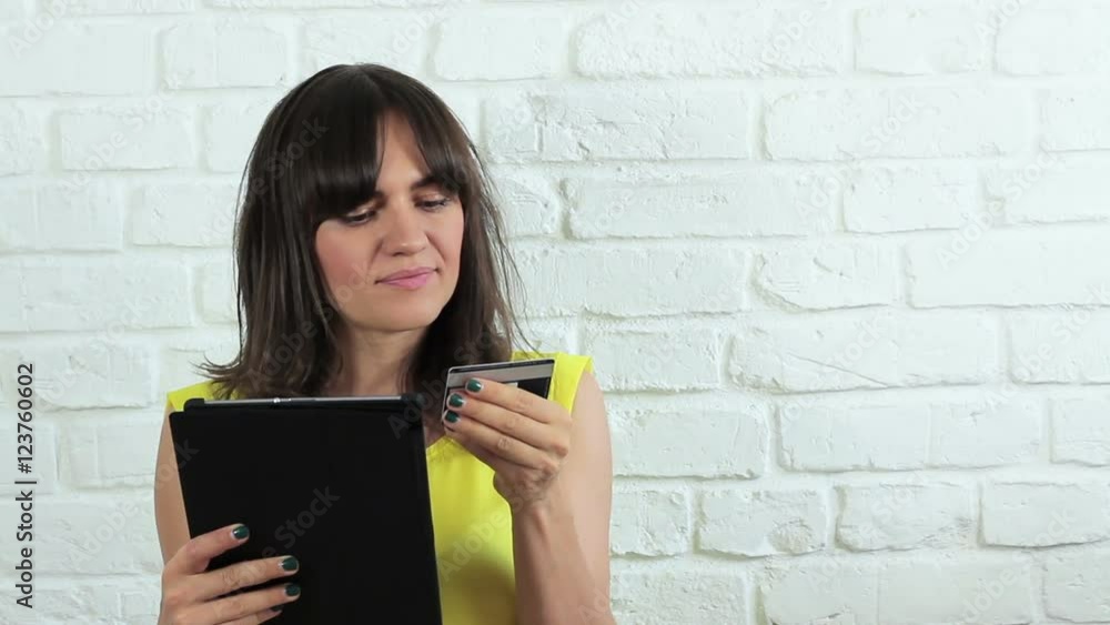 Cheerful young woman using her tablet computer and credit card for home shopping Cheerful young woman using her tablet computer and credit card for home shopping