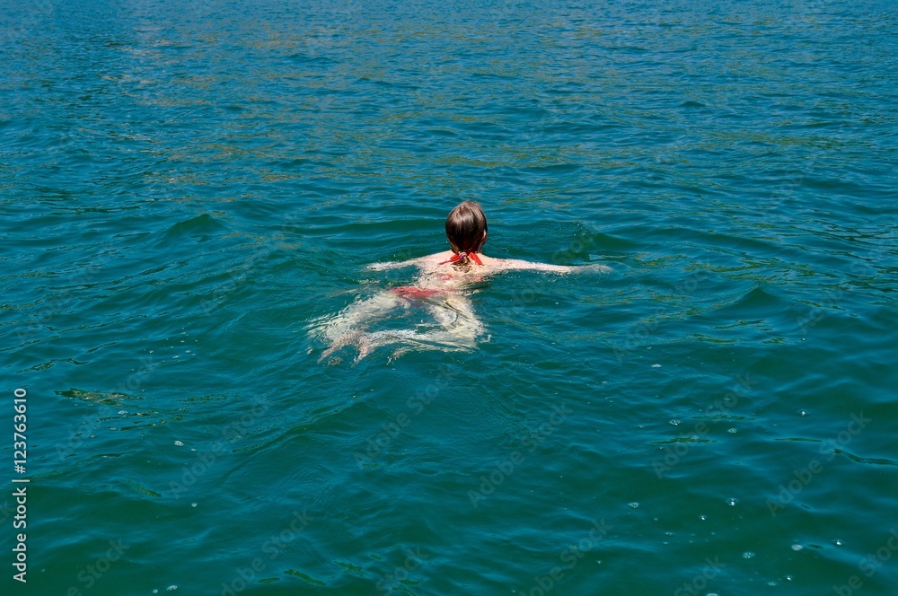 Junge Frau am Schwimmen im türkisblauen See - Brustschwimmen