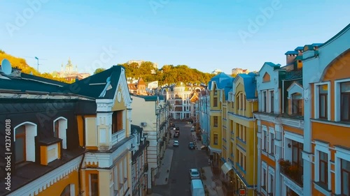 Drone Camera Moves at the Level of the Roofs of Buildings on the Old Narrow European Streets with Colorful Houses and Pedestrians at Sunset, Shot in 4K UHD