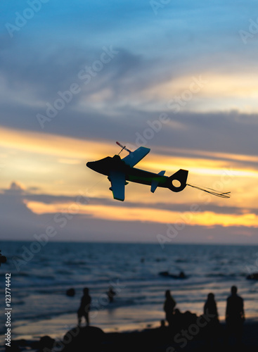 Air plane toy silhoette on the bech with sunset blur background.