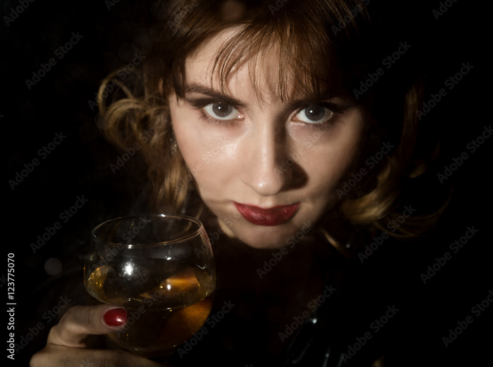 mysterious young woman with a glass of wine posing behind transparent glass covered by water drops. on a dark background mysterious young woman with a glass of wine posing behind transparent glass covered by water drops. on a dark background