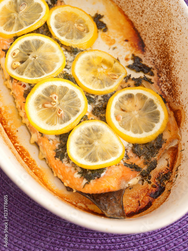 Baked salmon fillet in casserole, topped with lemon slices. Clos