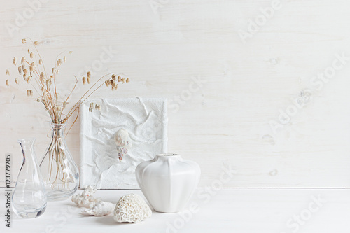 Soft home decor. Seashells and glass vase with spikelets on white wood background. Interior.