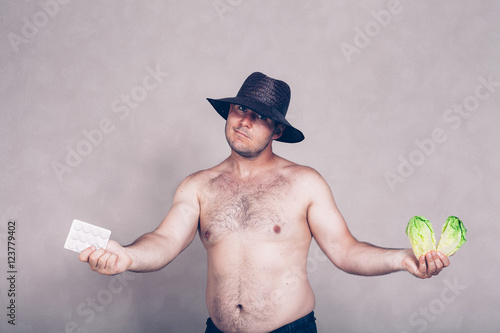Naked corpulent man giving pharmaceuticals and vegetable