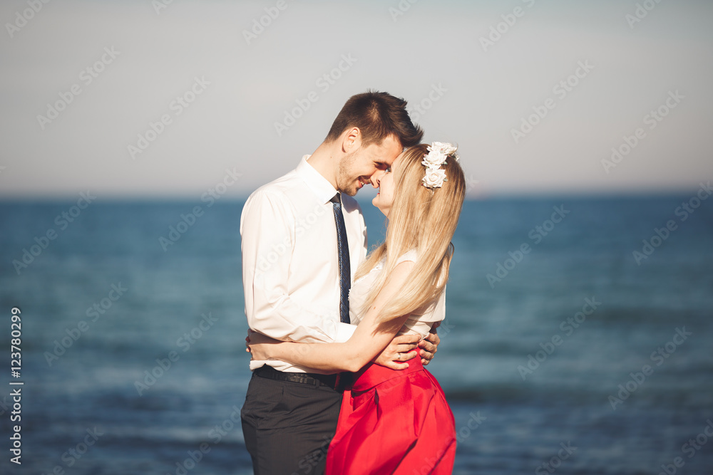Young happy couple walking on beach smiling holding around each other. Love story Young happy couple walking on beach smiling holding around each other. Love story