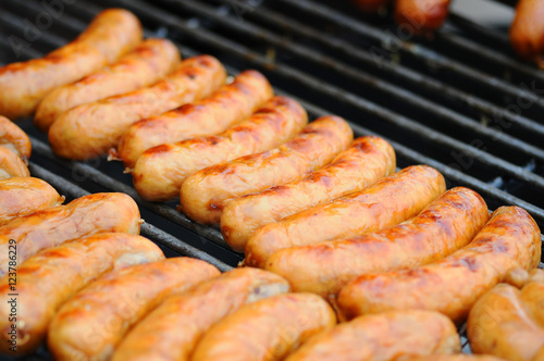 Fresh sausage and hot dogs grilling outdoors on a gas barbecue grill. Closeup of sausage on the grill