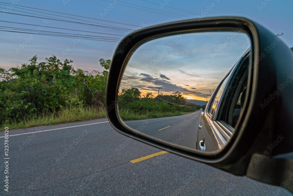 Reflection seen through car side mirror - two-lane winding road with twilight sky and sunset
Reflection seen through car side mirror - two-lane winding road with twilight sky and sunset