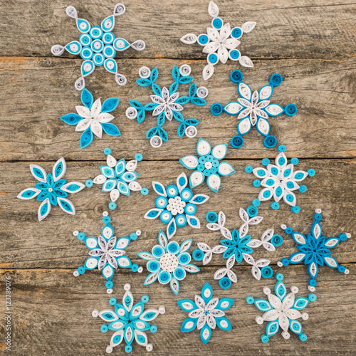 Paper snowflakes made with quilling technique on a wooden surface