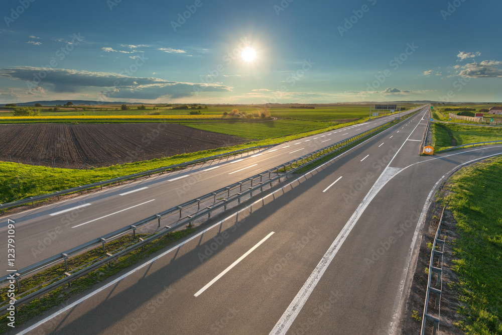 Open freeway through illuminated green agricultural fields Open freeway through illuminated green agricultural fields