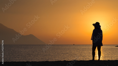 Woman standing and watching sunset against sun
