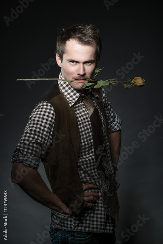 Young man with mustache and dry rose in the mouth